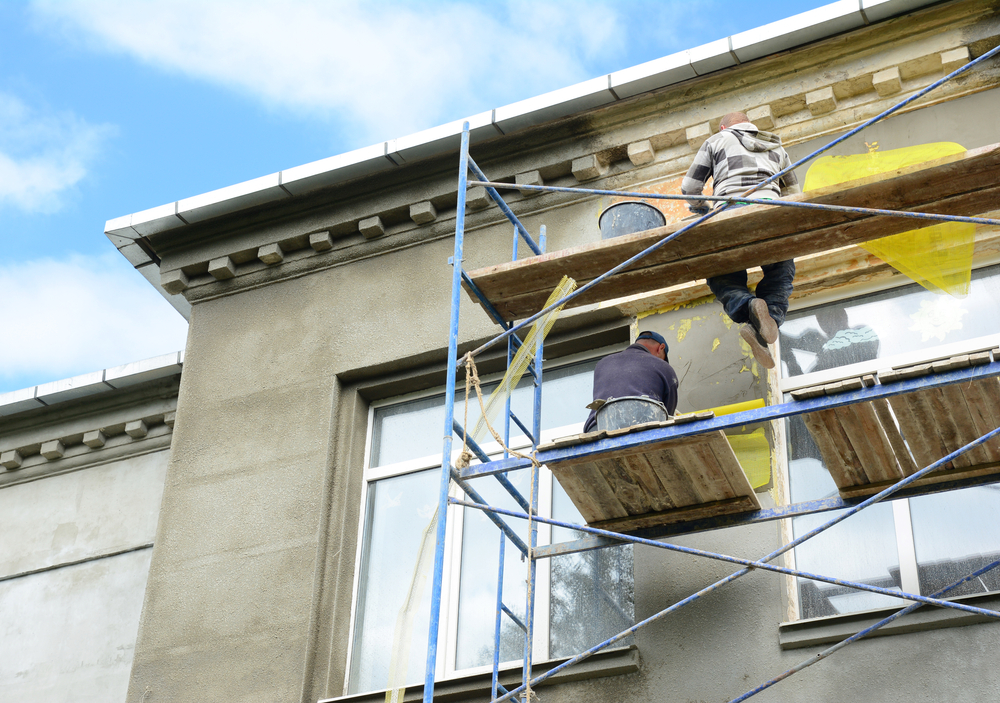 Building,Contractors,On,Scaffolding,Near,Rooftop,Are,Rendering,,Plastering,,Stucco couvreur à Andrézieux-Bouthéon